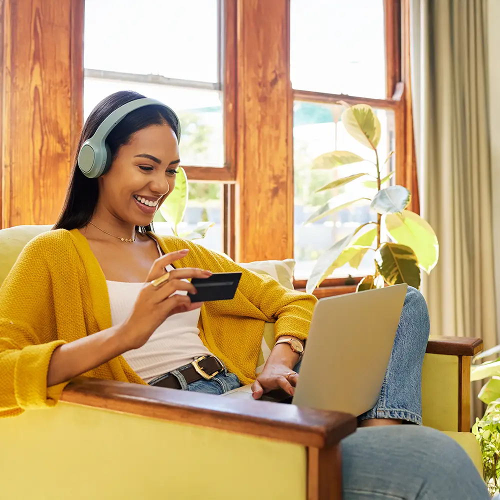 Woman shopping online from home using a laptop and holding a credit card