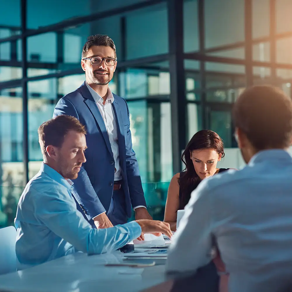 Business meeting with four people gathered around a table in a modern office.