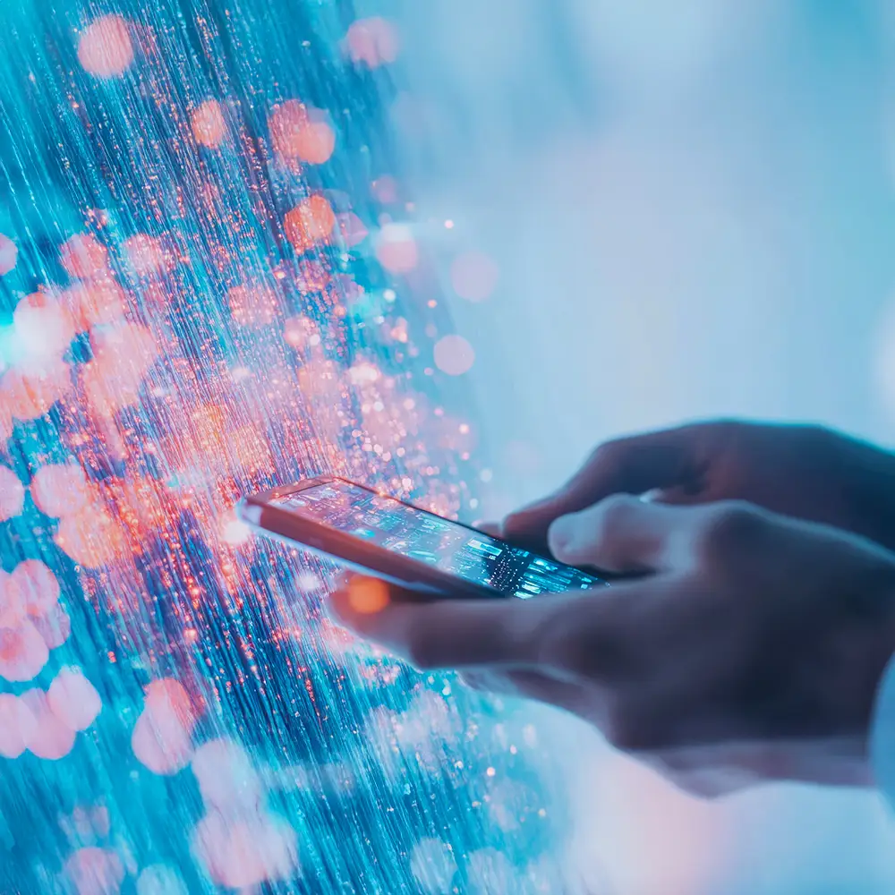 Hands holding a smartphone with abstract digital light effects in the background.