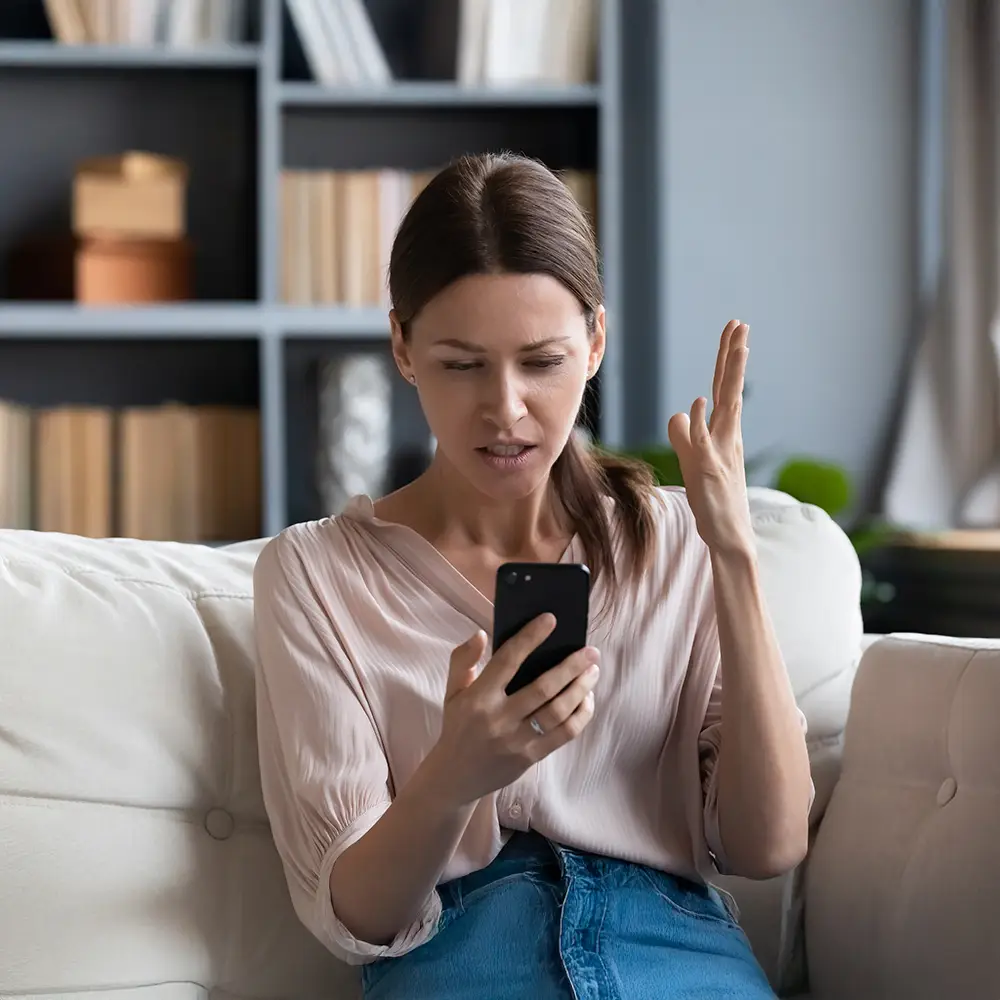 Woman looking frustrated while checking her smartphone.